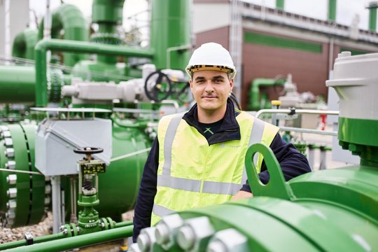 Ein Mitarbeitender steht zwischen Leitungsrohren, angelehnt