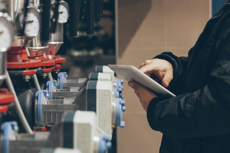 Druckventile einer technischen Anlage, Hände am Tablett bei der Eingabe der Druckstände